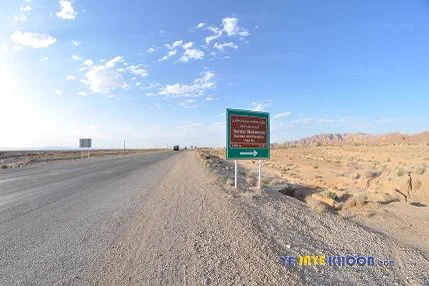 جاده و تابلو ای در میان آن در حال اشاره به عمارت سردار مکرم